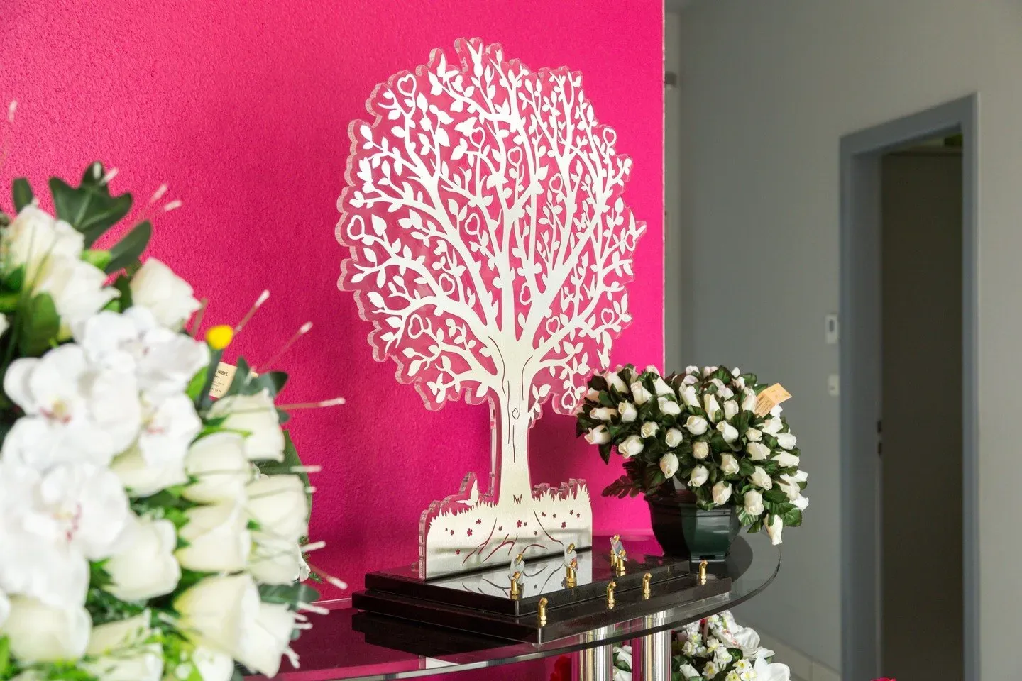 Ornement funéraire en forme d'arbre de vie blanc sur mur fuchsia.