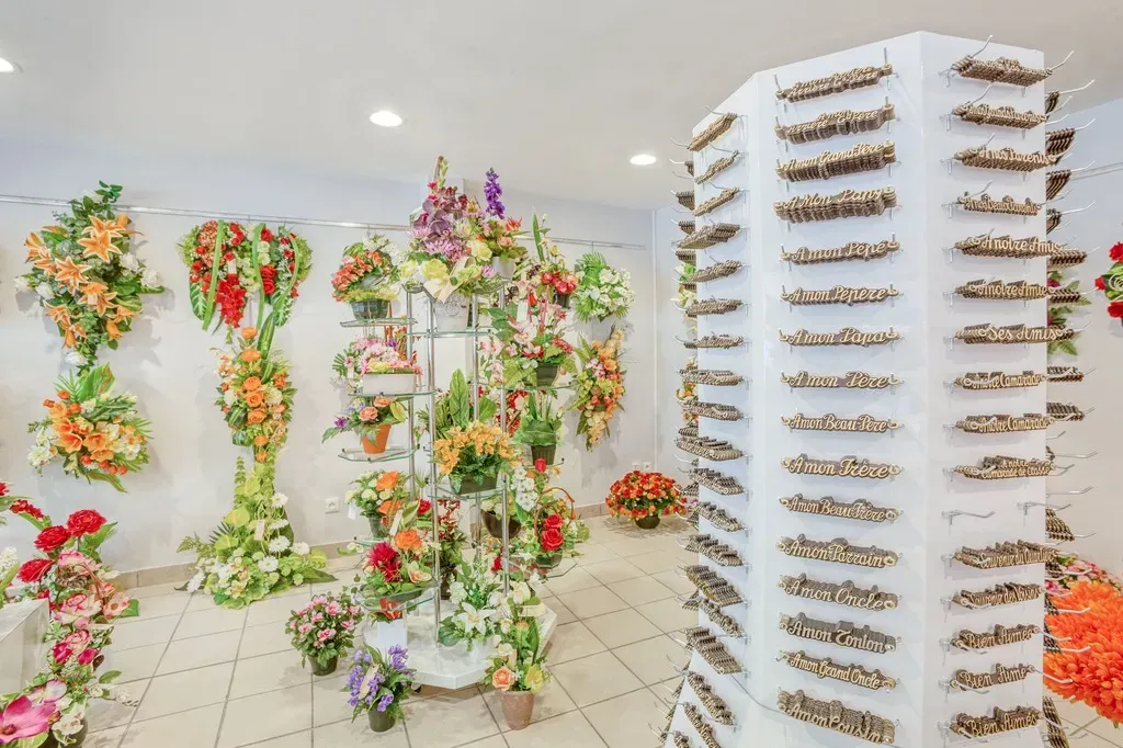 Présentoir d'inters funéraires gravés et fleurs de deuil en magasin.
